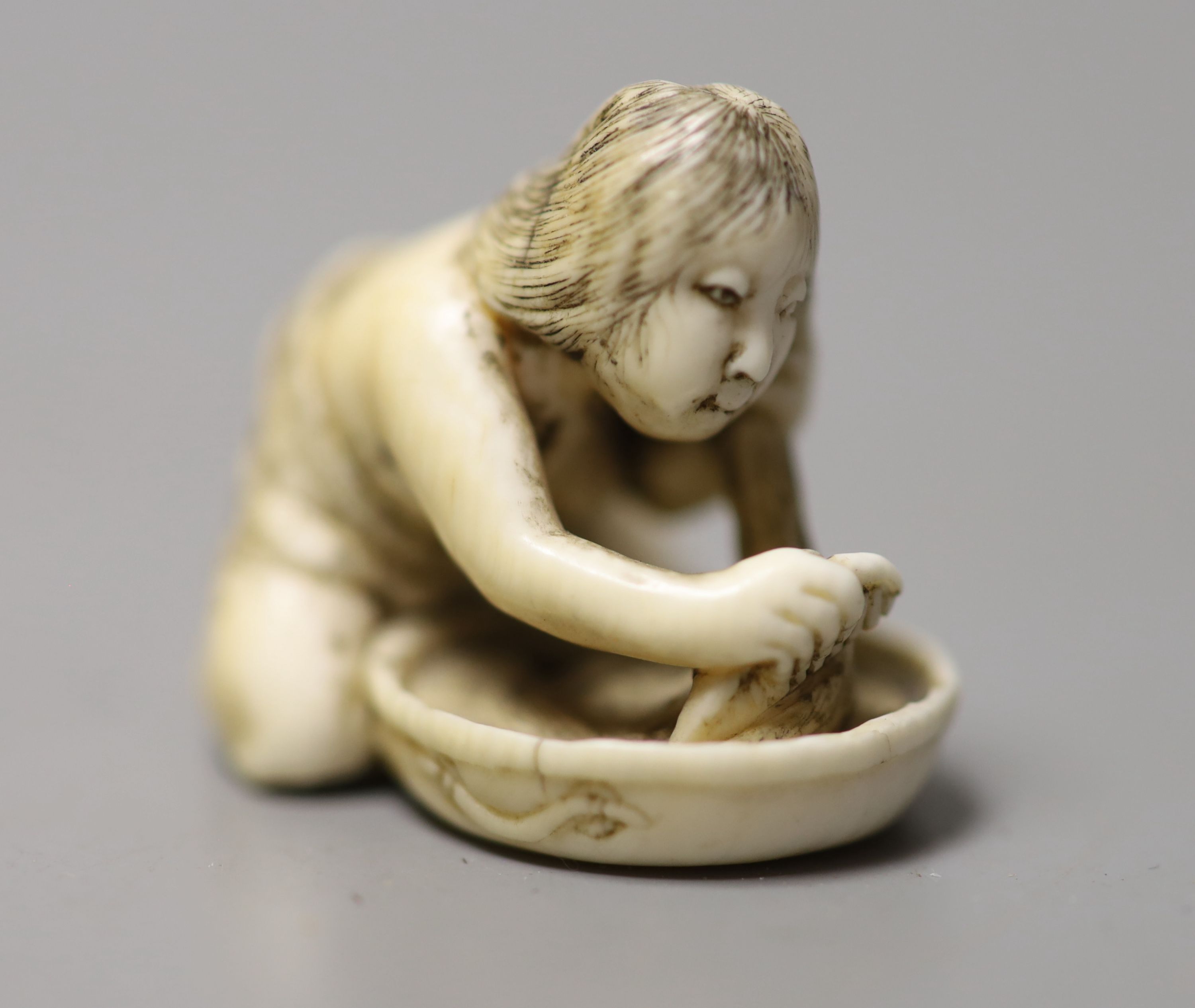 A 19th century Japanese ivory netsuke of a woman washing her hair, 3.5cm wide